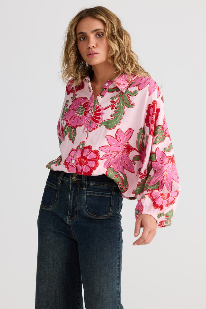 Woman wearing a floral blouse and jeans on a white background