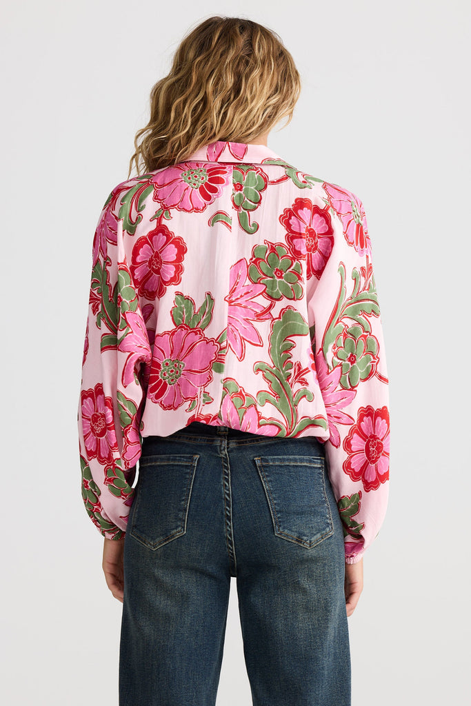 Person wearing a pink floral blouse and blue jeans on a white background