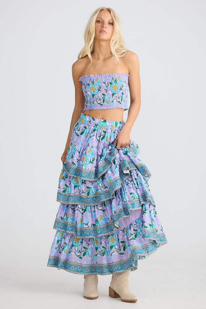 Woman wearing a floral two-piece outfit with a top and tiered skirt on a white background