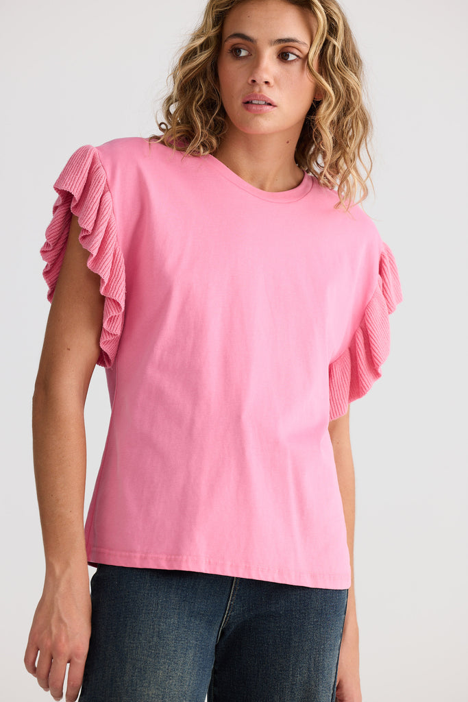 Woman wearing a pink top with ruffled sleeves on a white background