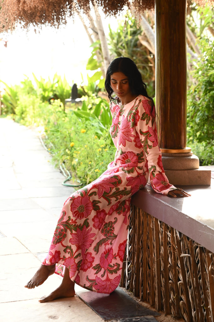 Person in a floral dress sitting on a bench with greenery in the background