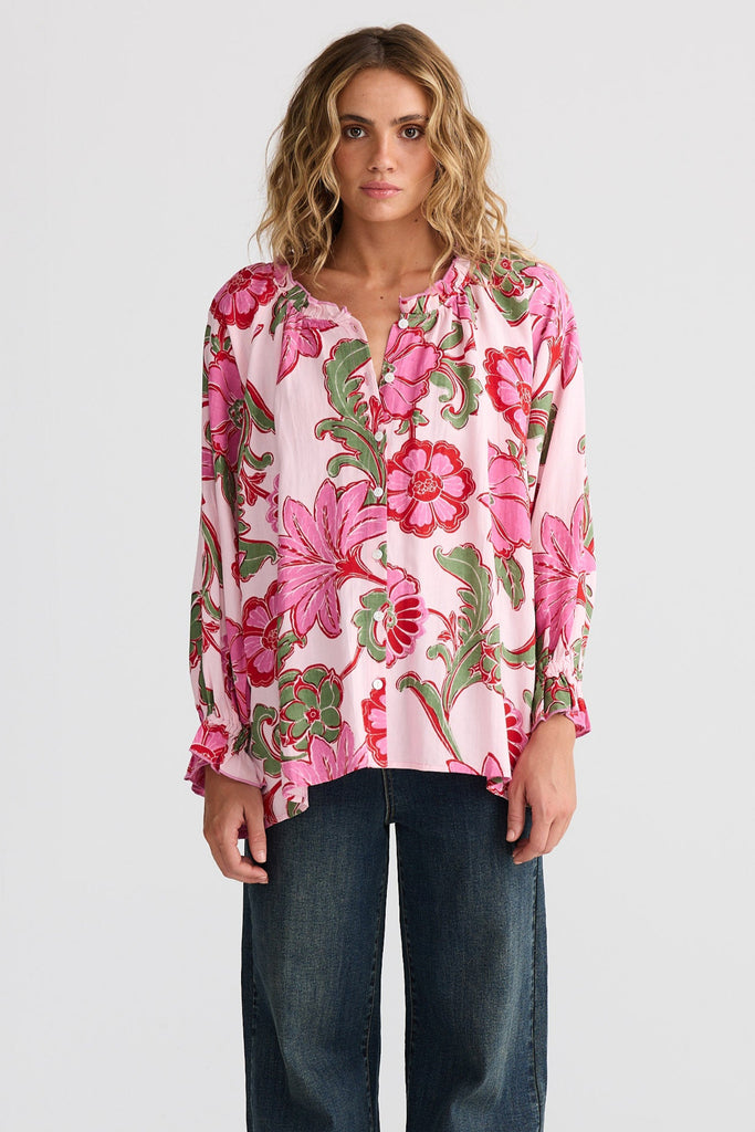 Woman wearing a floral blouse and jeans on a white background