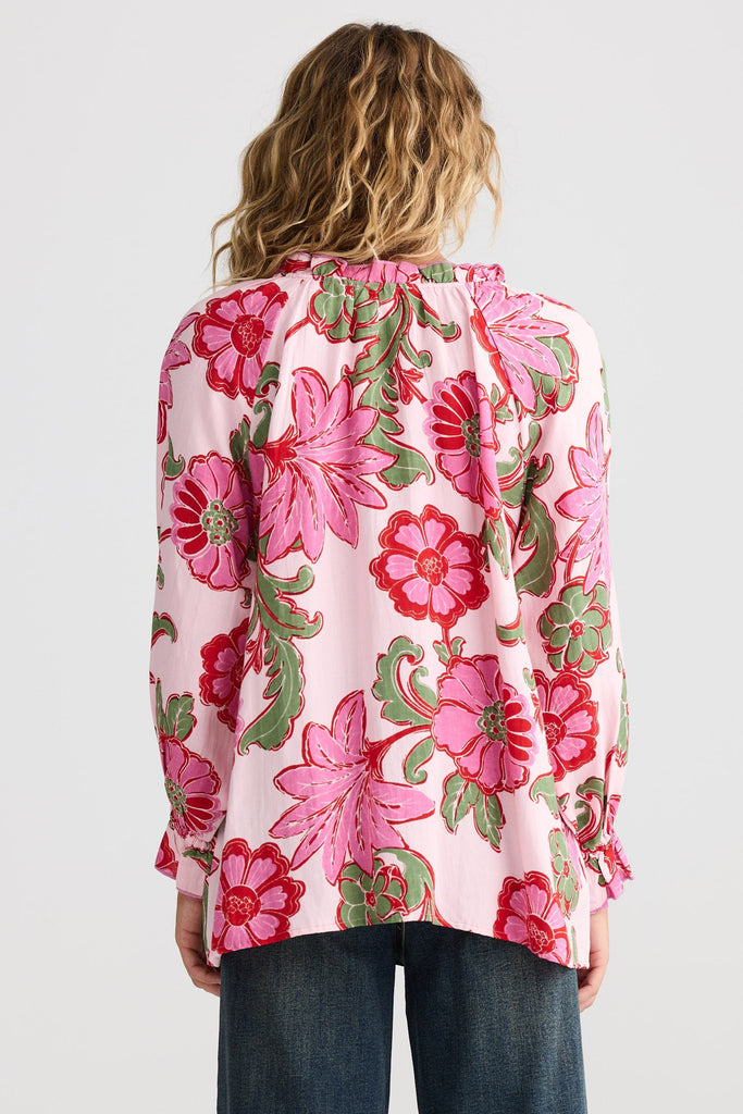 Person wearing a pink floral blouse with a plain background