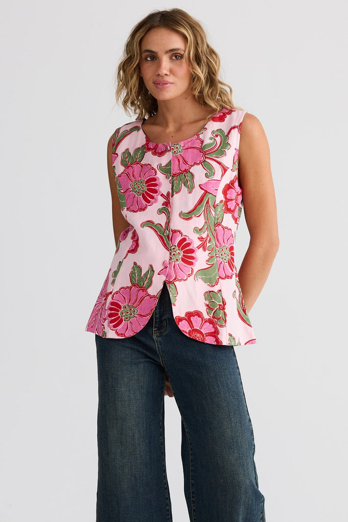 Woman wearing a floral sleeveless top and jeans on a white background