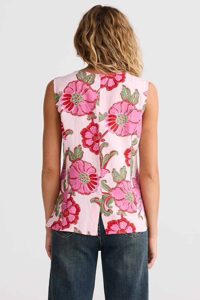 Woman wearing a sleeveless floral top with pink flowers on a plain background