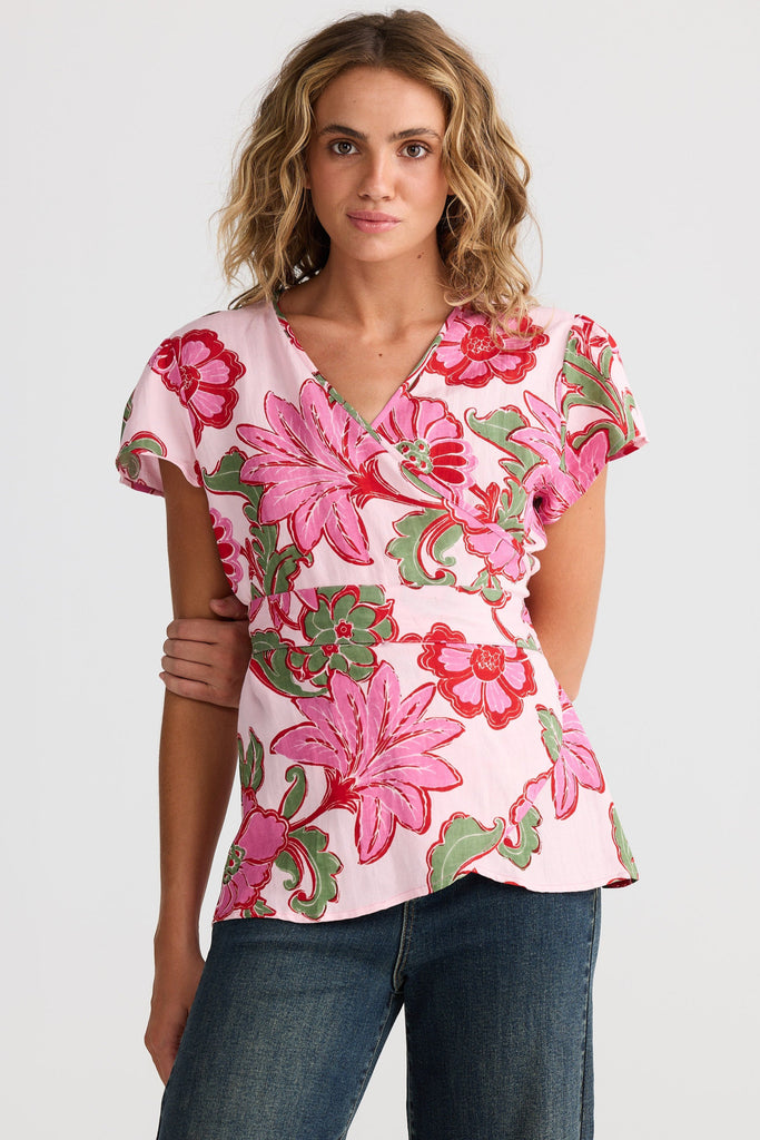 Woman wearing a pink floral blouse and blue jeans on a white background