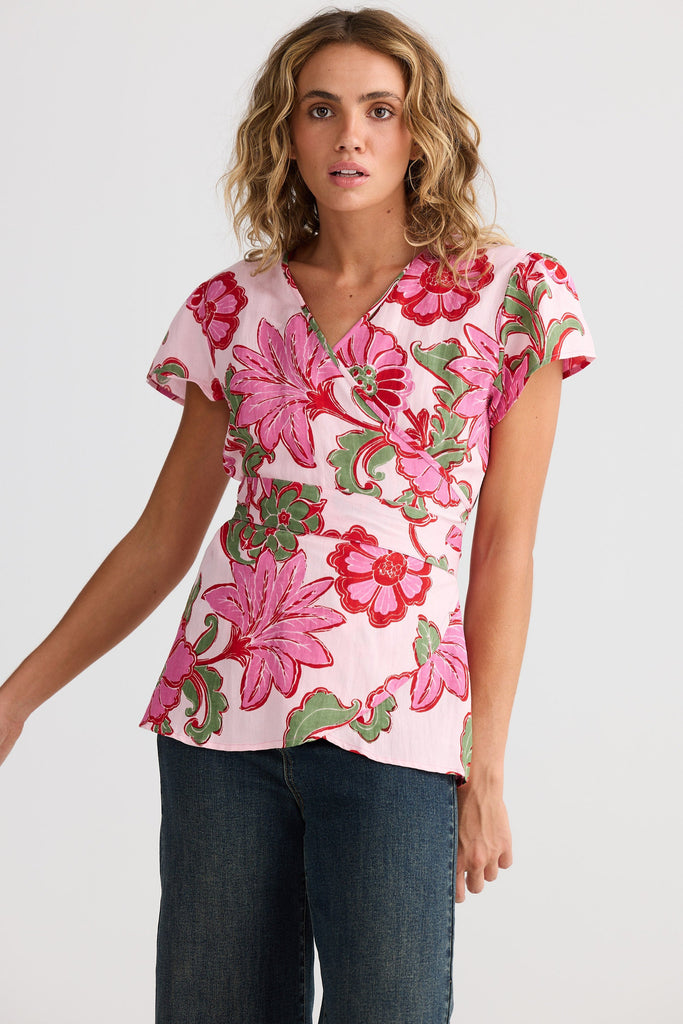 Woman wearing a pink floral blouse with a plain background