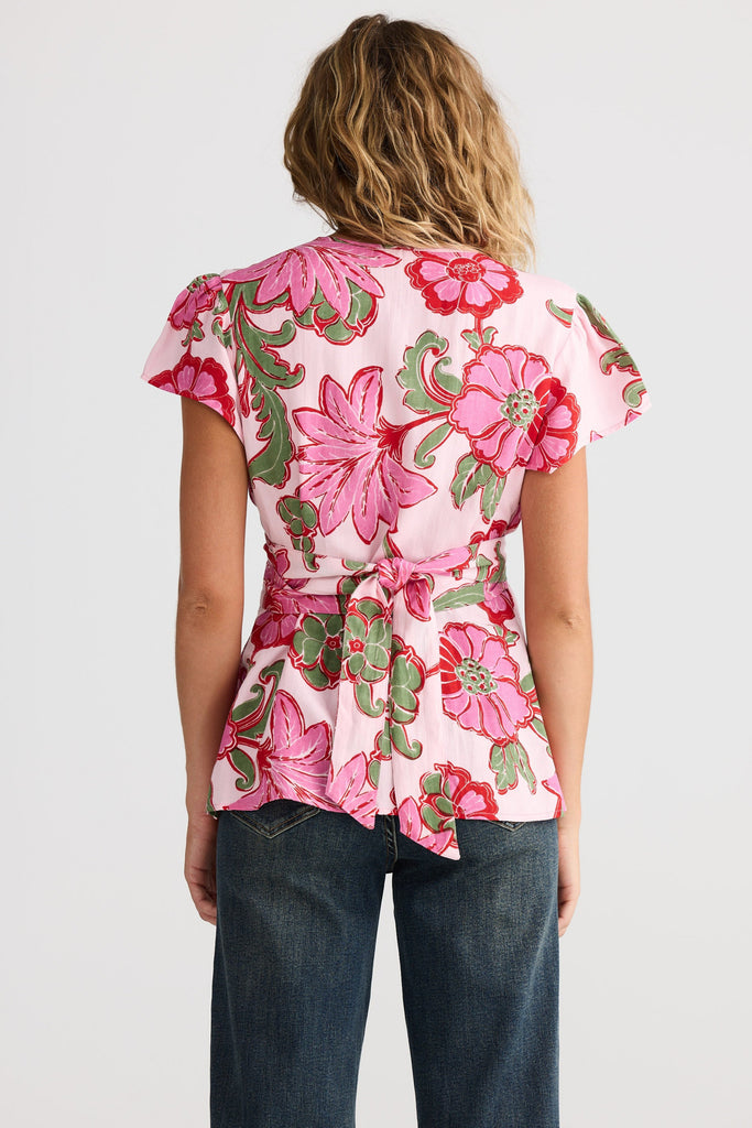 Person wearing a pink floral top with a plain background