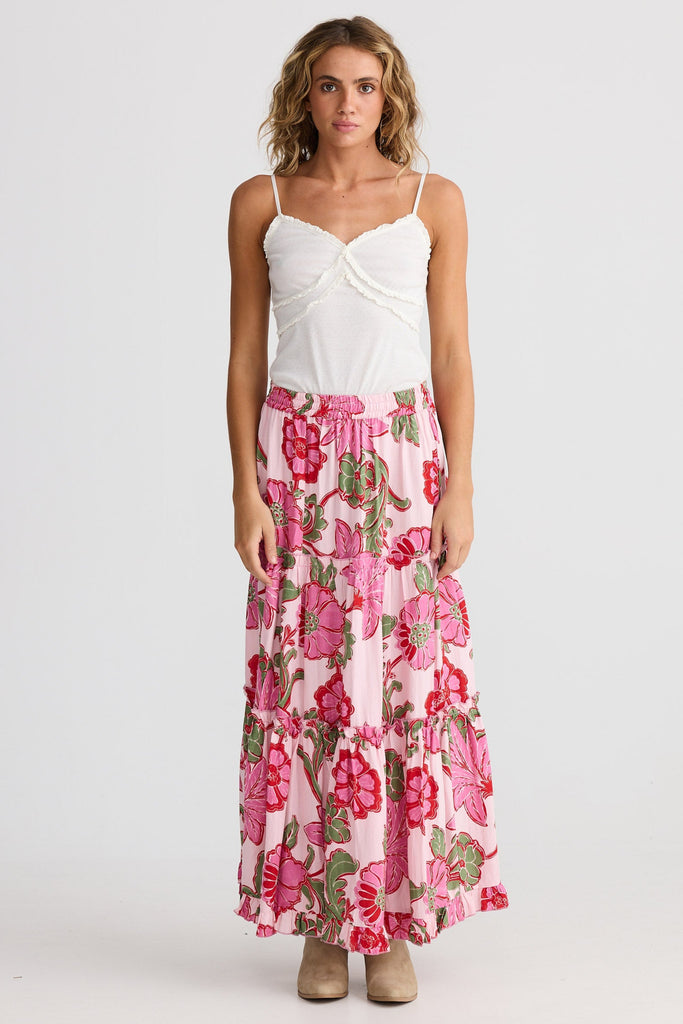 Woman wearing a white top and pink floral skirt on a white background