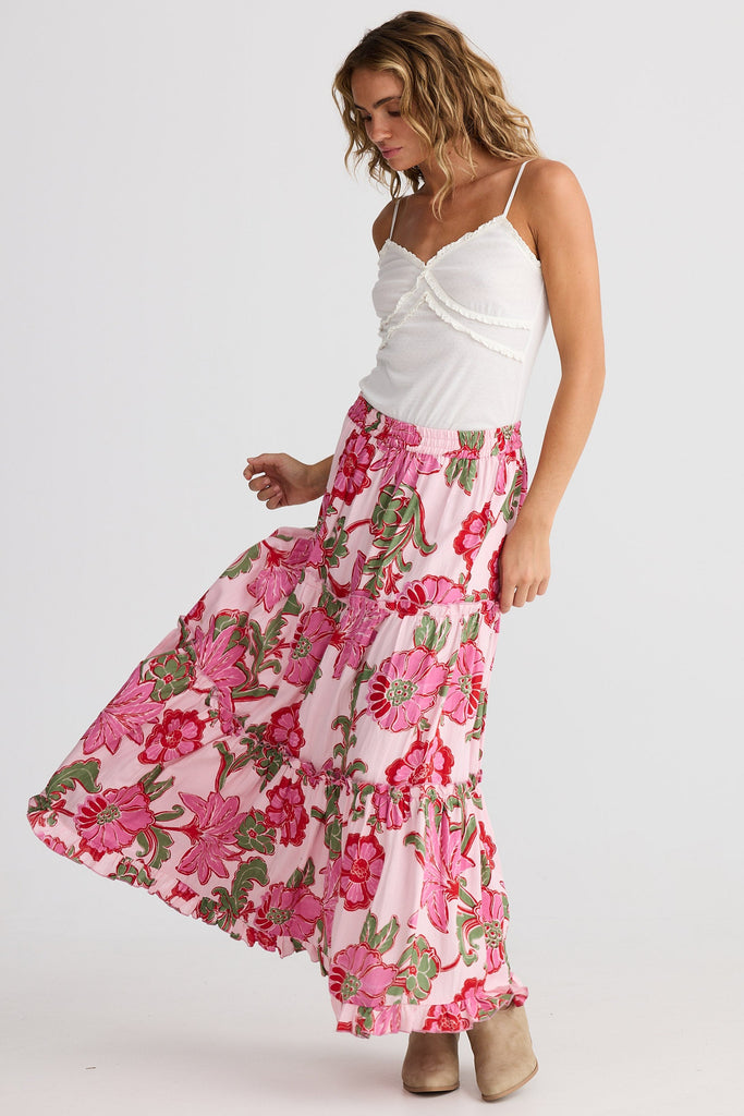 Woman wearing a white top and pink floral skirt on a white background