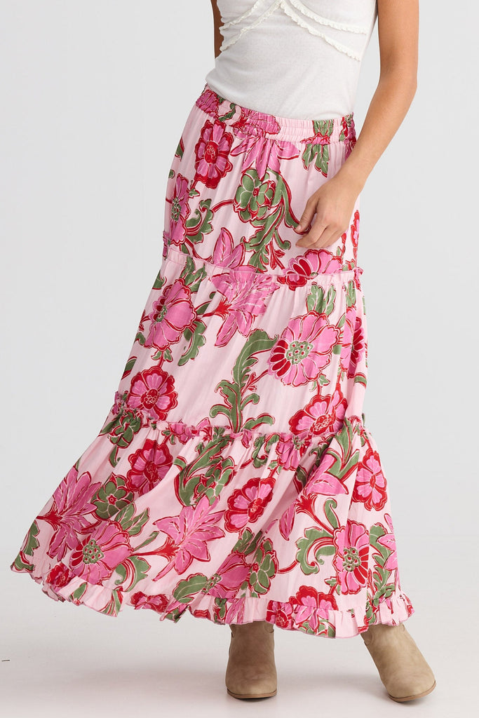 Woman wearing a white top and pink floral skirt on a white background