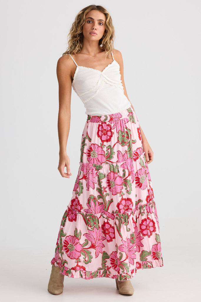 Woman wearing a white top and pink floral skirt on a white background