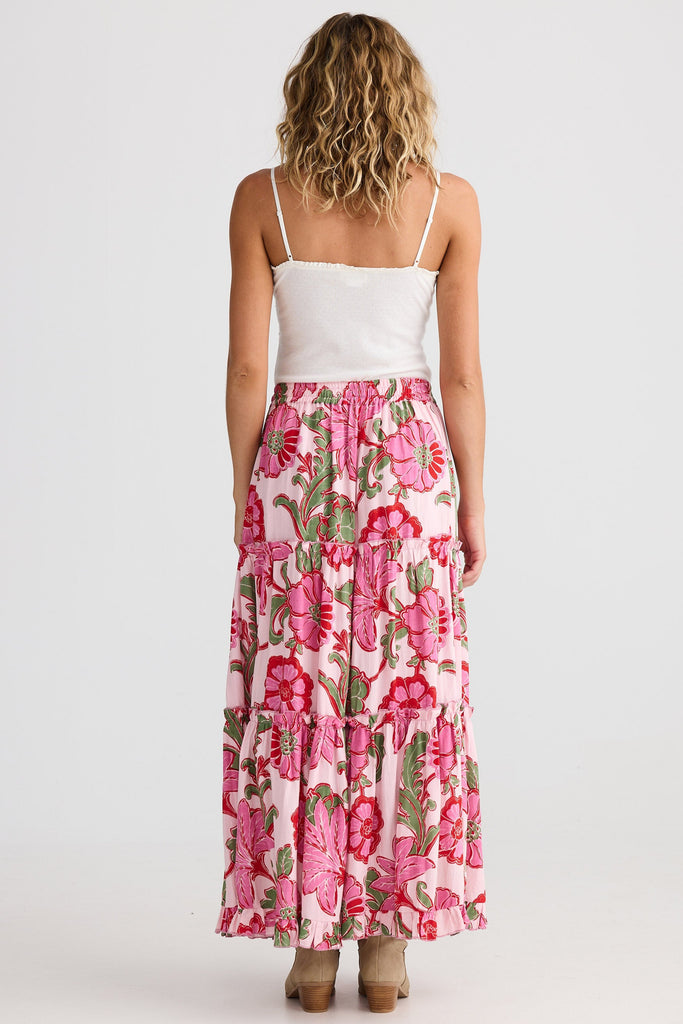 Woman wearing a white top and pink floral skirt on a white background