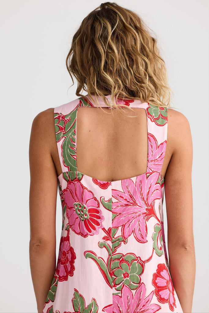 Woman wearing a floral dress with pink and green flowers on a plain background