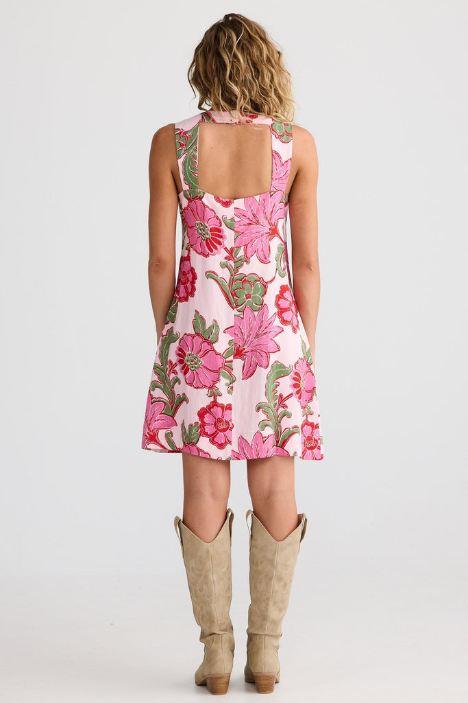 Woman wearing a floral dress with beige boots on a white background