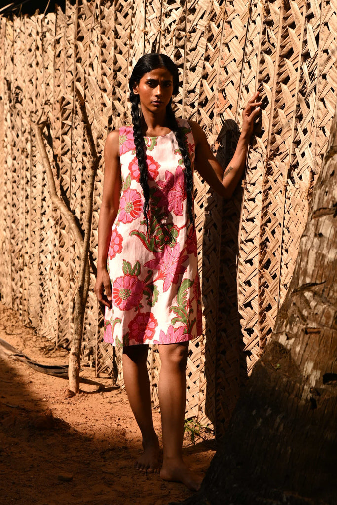 Woman standing next to a woven fence, surrounded by natural elements