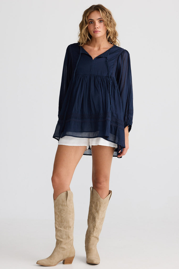 Woman wearing a navy blue top and beige knee-high boots on a white background