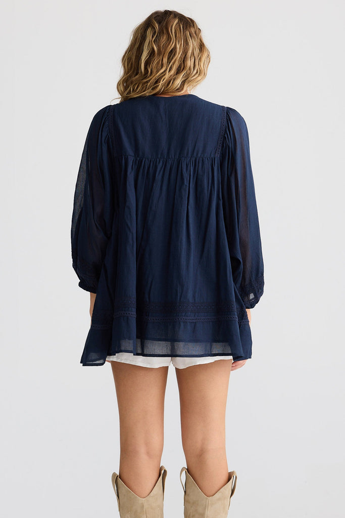 Person wearing a navy blue blouse and beige knee-high boots on a white background