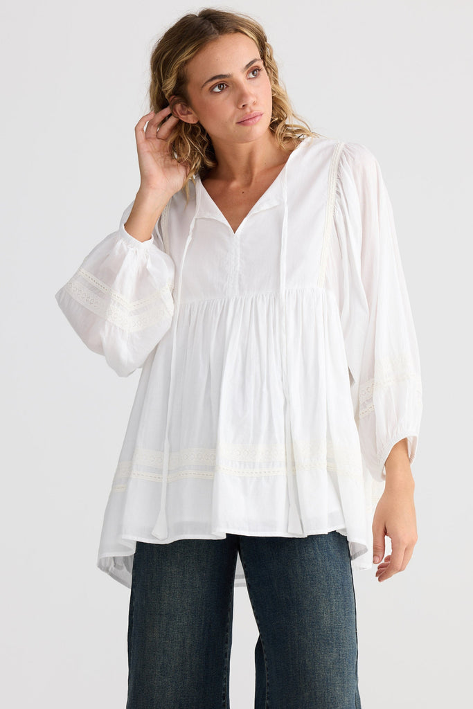 Woman wearing a white blouse and blue jeans on a white background