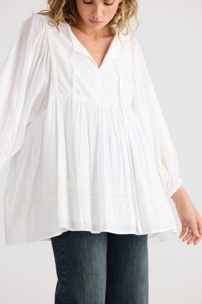 Woman wearing a white blouse and blue jeans on a plain background