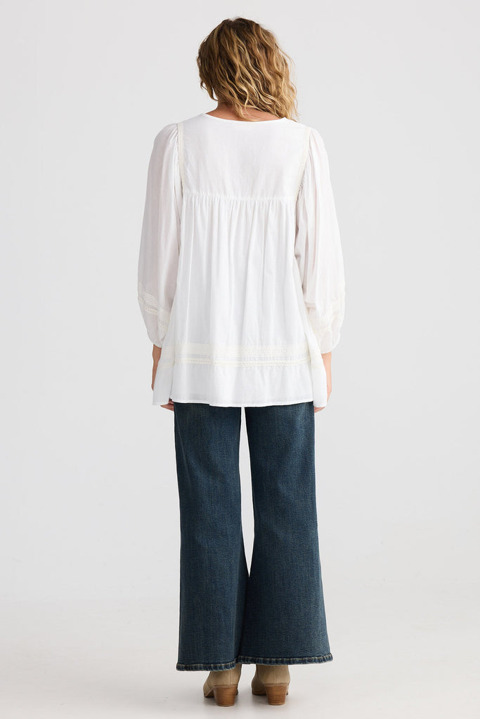 Person wearing a white blouse and dark blue jeans on a white background