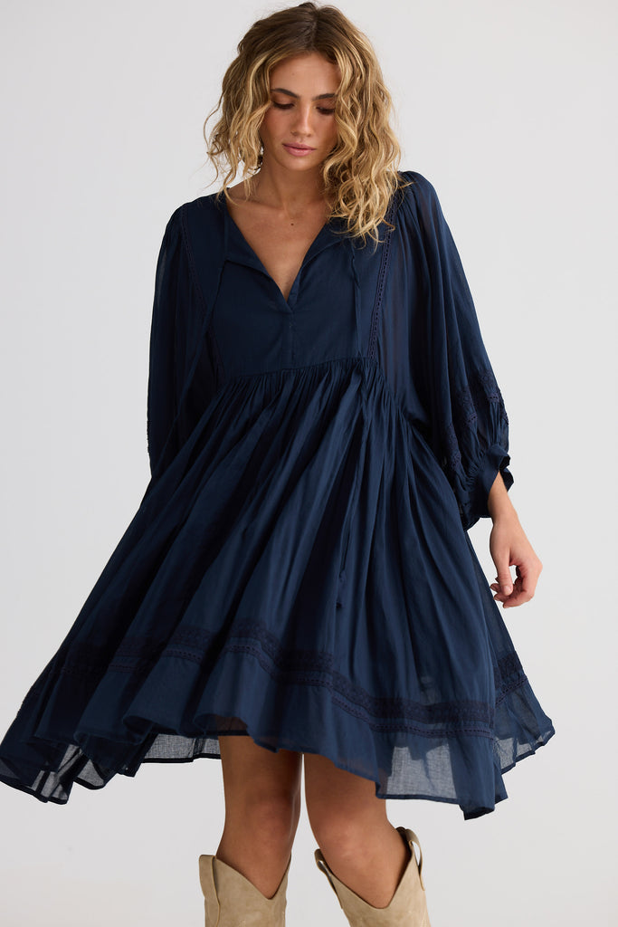 Woman wearing a navy blue dress with long sleeves on a white background