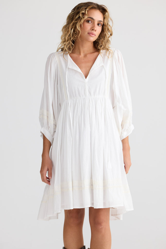 Woman wearing a white dress with a plain background