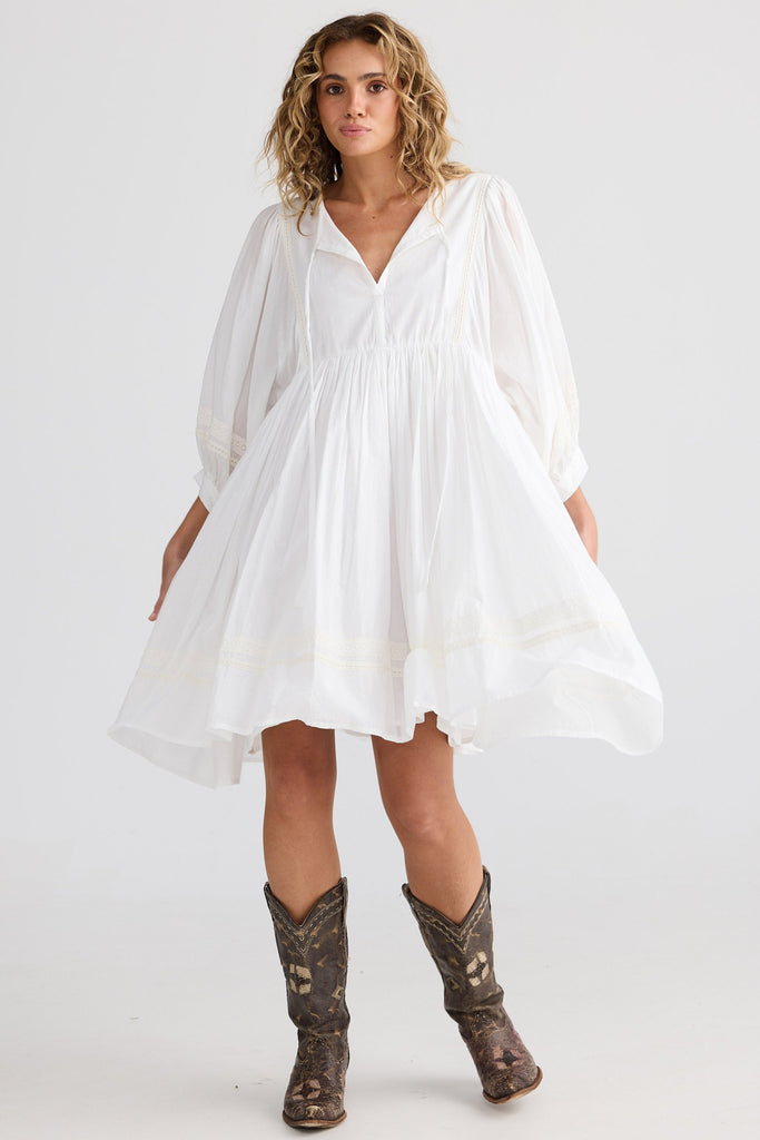 Woman wearing a white dress and brown boots on a white background
