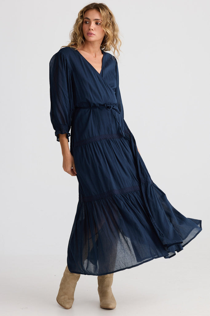 Woman wearing a long navy dress on a white background