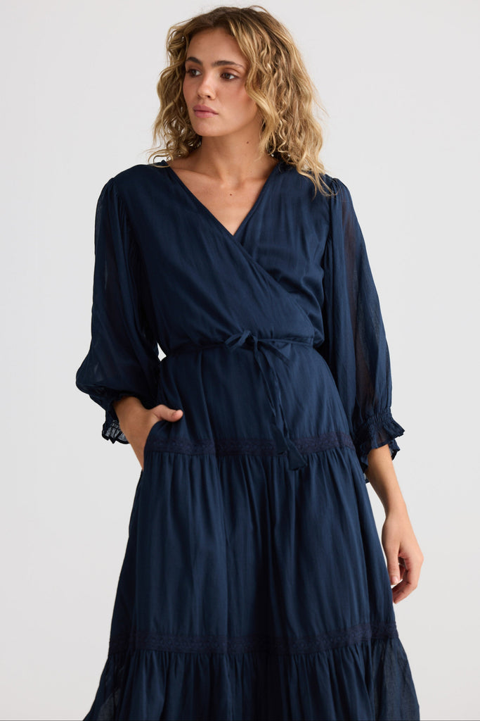 Woman wearing a navy blue dress with a plain background