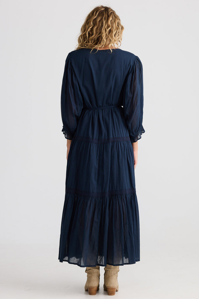 Woman wearing a navy blue dress with long sleeves on a white background