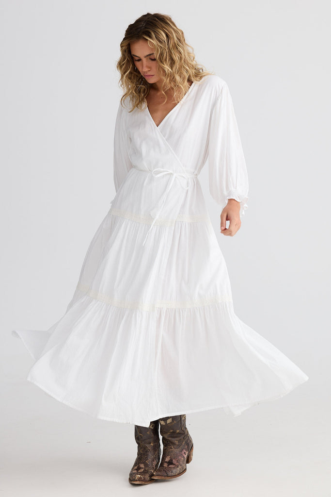 Woman wearing a white dress with long sleeves on a plain background