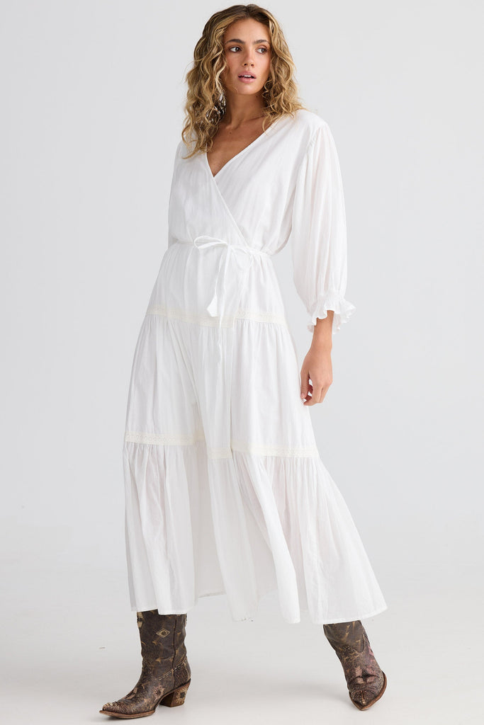 Woman wearing a white dress with brown boots on a white background