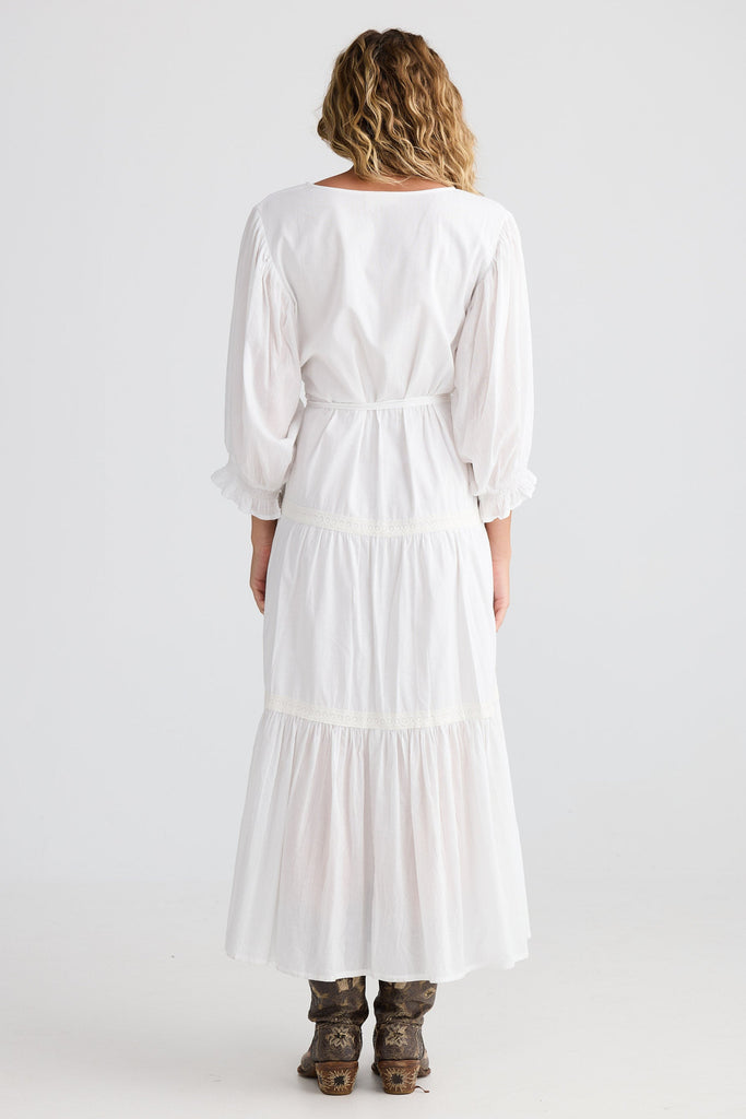Woman wearing a white dress with long sleeves and a belt on a white background