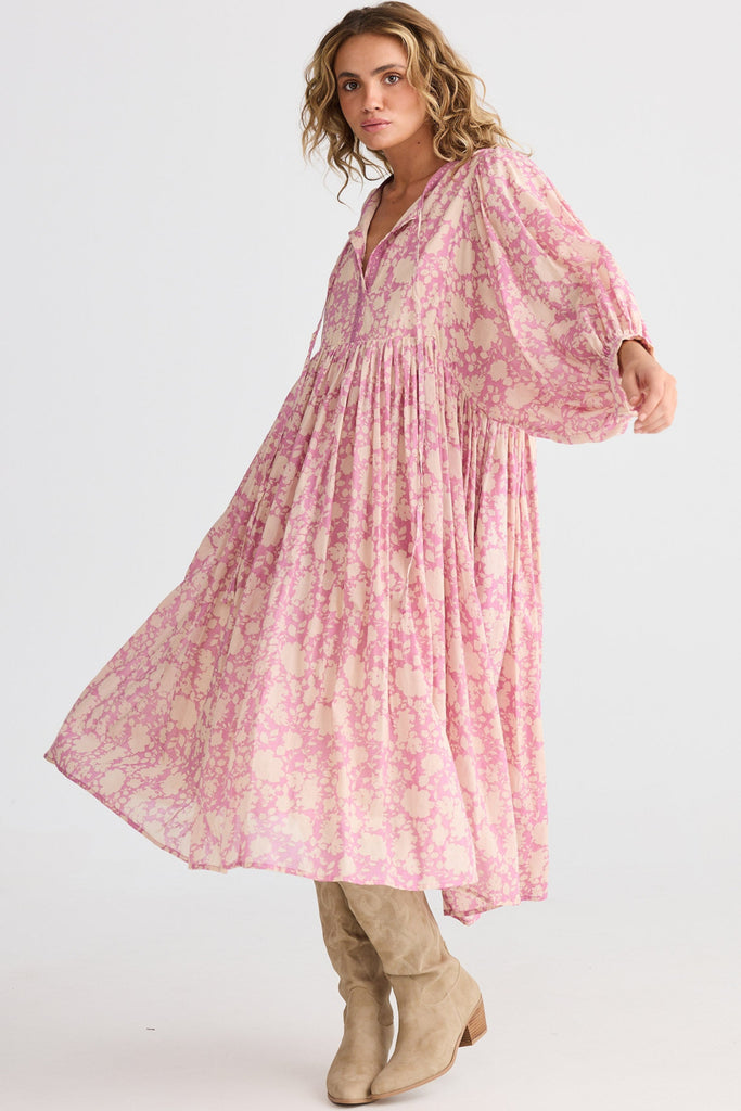 Woman wearing a pink floral dress with beige boots on a white background