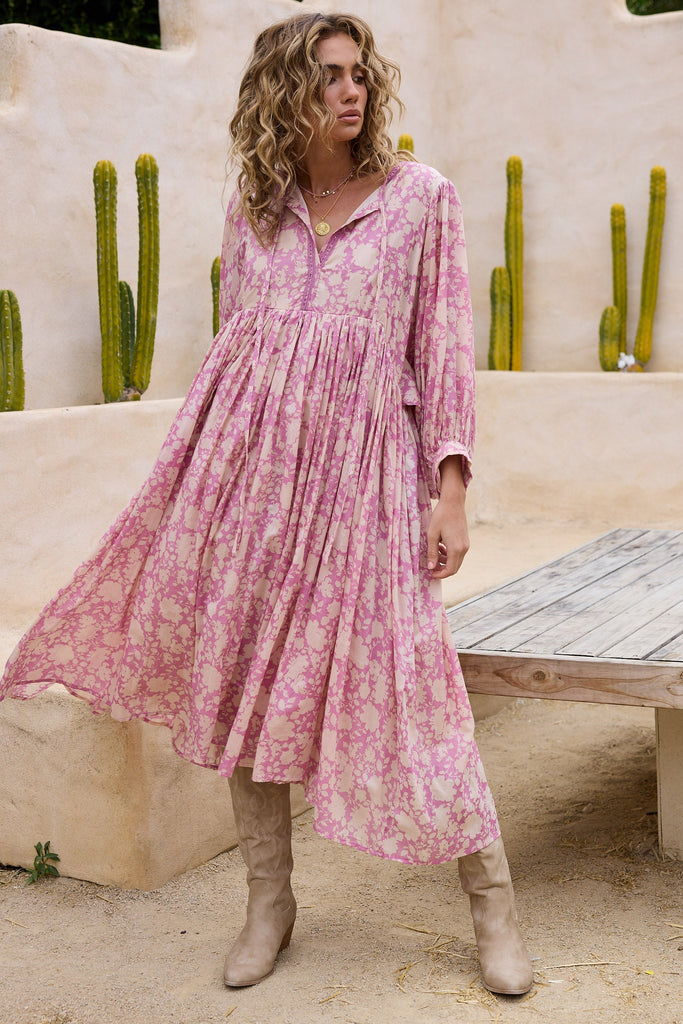 Woman in a pink dress standing in front of cacti