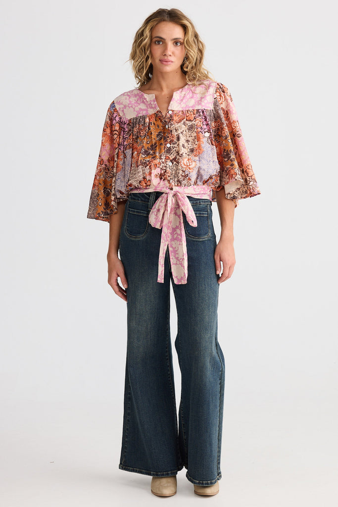 Woman wearing a floral blouse and jeans on a white background