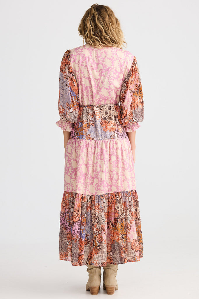 Woman wearing a long, patterned dress with a white background