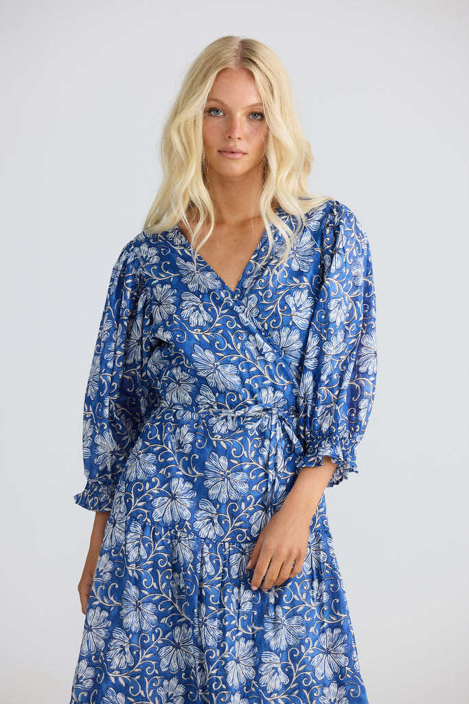 Woman wearing a blue floral dress against a white background