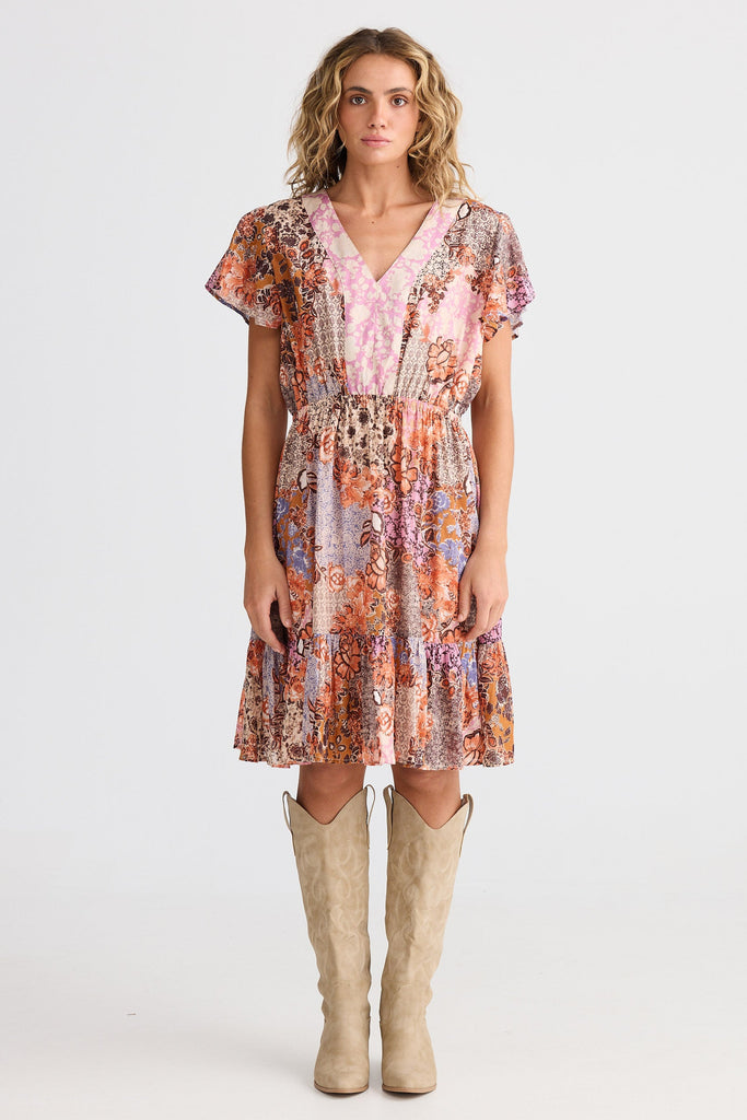 Woman wearing a patterned dress and beige boots on a white background