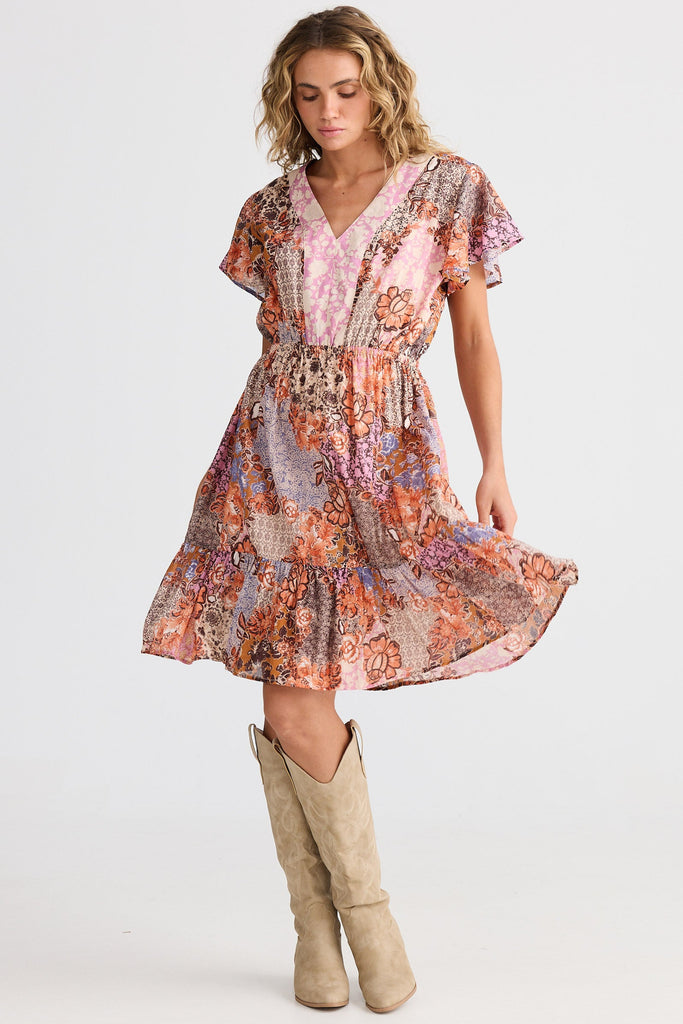 Woman wearing a floral dress with knee-high boots on a white background