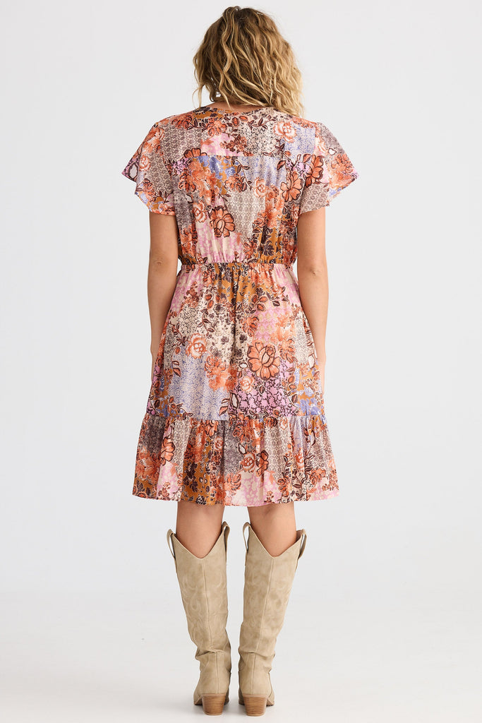 Woman wearing a floral dress with cowboy boots on a white background