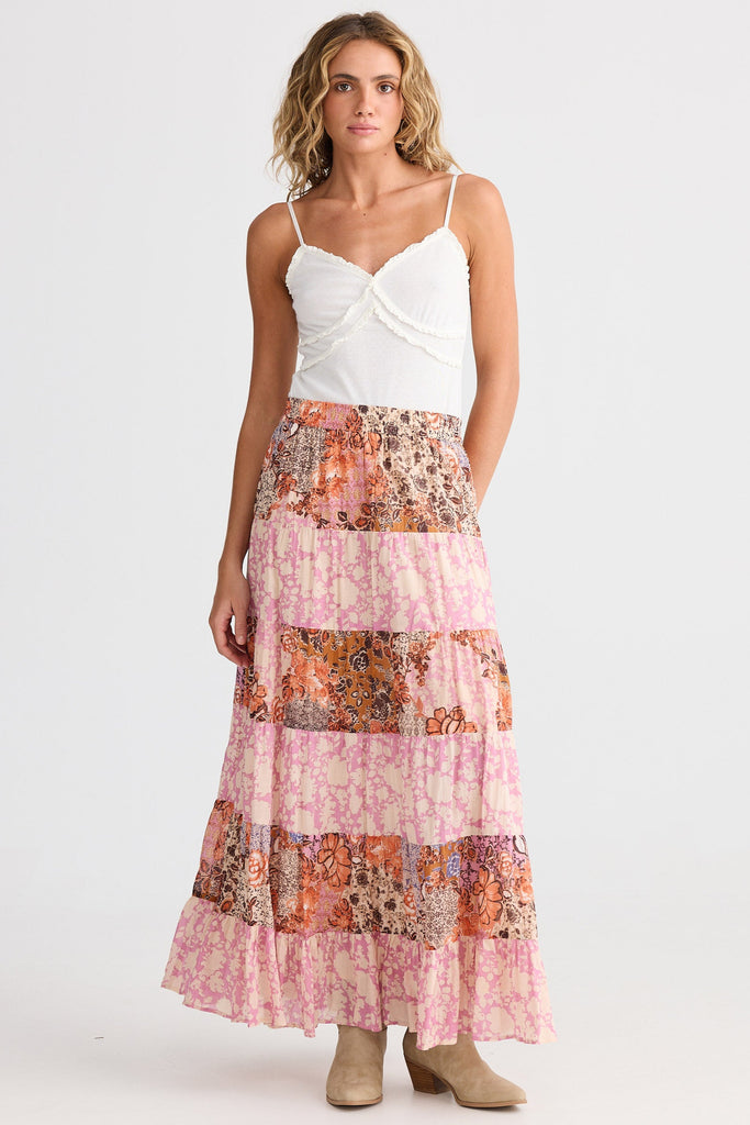 Woman wearing a white top and floral patchwork skirt on a white background