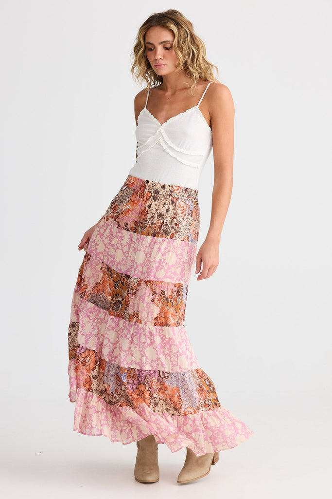 Woman wearing a white top and floral tiered skirt on a white background