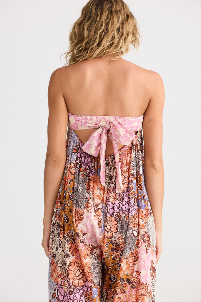 Woman wearing a floral strapless dress with a bow detail on a plain background