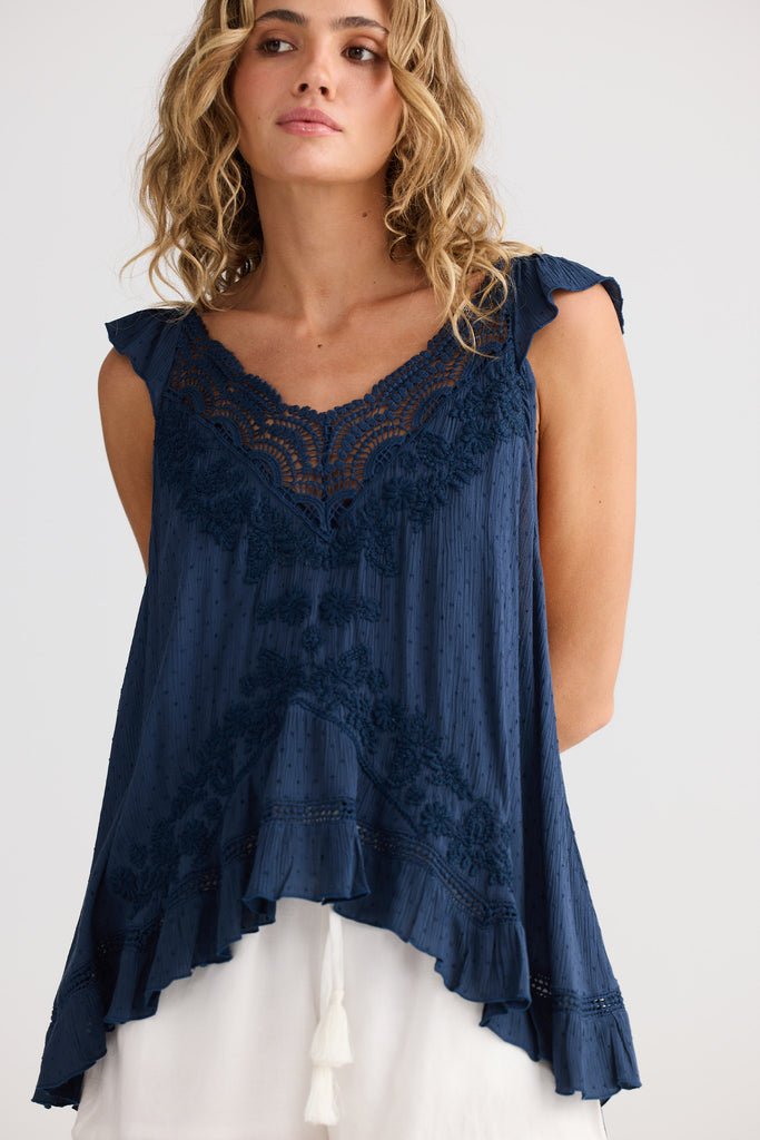 Woman wearing a navy blue lace top against a white background