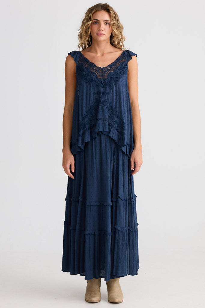 Woman wearing a navy blue dress with lace details on a white background
