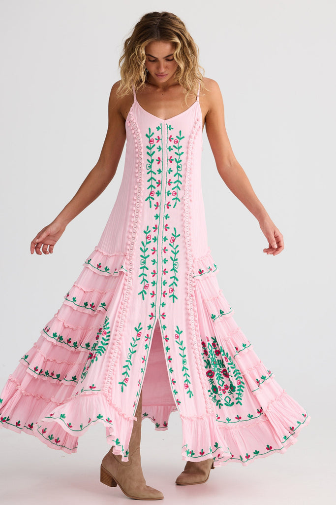 Woman wearing a pink dress with green floral patterns on a white background