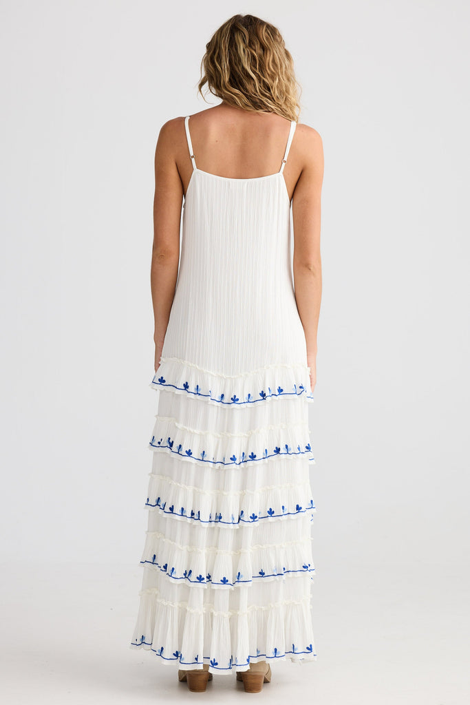 Woman wearing a white dress with blue details on a plain background