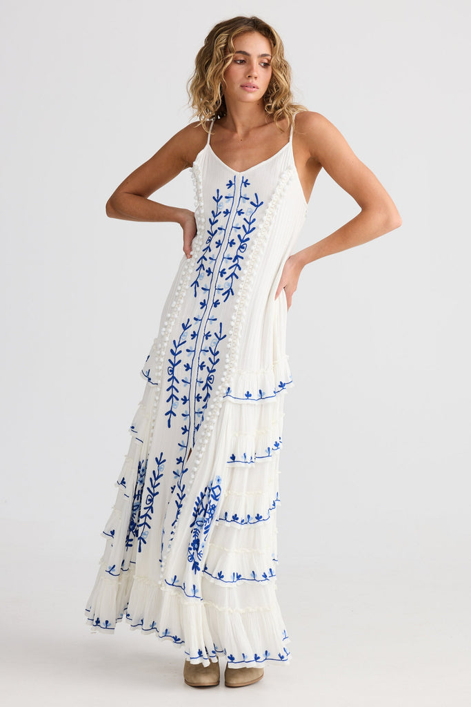 Woman wearing a white dress with blue floral patterns on a plain background